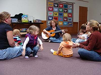 Kathryn Russell (with guitar) leads children in song, dance, and playing musical instruments ecm_singing
