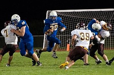Darren Sill and # 64, John Sterle manhandle a couple of defensive linemen to create a hole for # 30 Greg Lehr to run through. footballv0905_lehr