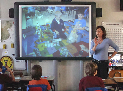 Third Grade Teacher Pamela Bryce shows pictures of the bake sale during Friday's awards ceremony brycecsa_slides