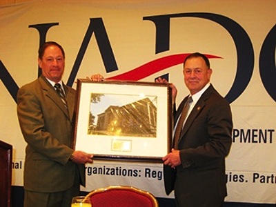 Pictured at left is Greg Eisenhut, Executive Director of the Mohawk Valley Economic Development District, Inc. (Mohawk, N.Y.) who presented Rep. Hanna with the award Wednesday during NADO’s Washington Policy Conference in Arlington, Virginia. Erik Miller, Director of the Southern Tier East Regional Planning Development Board (Binghamton, N.Y.), also represented the state’s regional councils at the event. hannaleg_400