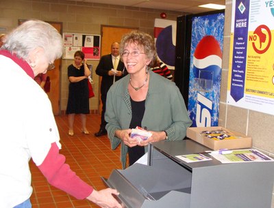 Tompkins County Legislature Chair Martha Robertson (right) makes the first deposit of unused medicines at the drop box in the lobby of the Public Safety Building. medreturn_robertson