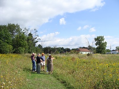 The eastern-most portion of the town center parcel was contaminated with petroleum in the old town Highway Department garage (seen in the distace. It is now rented by Scoops and Kersat Landscaping), so is not suitable for building. Sewer Committee members view that portion of the land proposed for dog park. tcwalk_dogpark