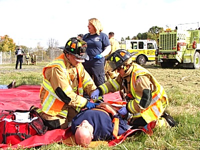 Lansing responders Dan Ferguson (left) and Kim Sweeney help a severely wounded man on the red tarp apdd ferguson-sweeney