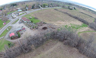 An aerial view of the start of the Murdock Spur. The red roof is Scoops, the new bridge is in the lower left-hand corner of the picture, the Murdock Spur begins as a brown path then turns to the right and follows the trees along the railroad line. The green path to the right of the tree line is part of the Lansing Center Trail. Lansing Center trail