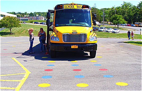 Dots have been painted on a parking lot near the bus garage so drivers can align their mirrors before driving. The dots define a 15'-around 'danger zone' that drivers need to be able to see as children get on and off their buses. Mirror Alignment