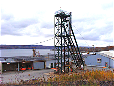 A steel structure houses pulleys and cables that transport the elevator from the surface to the mine, 2,300 feet below. A hoist operator performs test trips and follows normal safety protocols before the elevator is loaded and mine workers transported to the mine below. Small vehicles and trucks await them at the bottom, and it is typicalaly a 30 or 40 minute drive to the active mine sites to the north and well below Cayuga Lake. Cargill Elevator Shaft