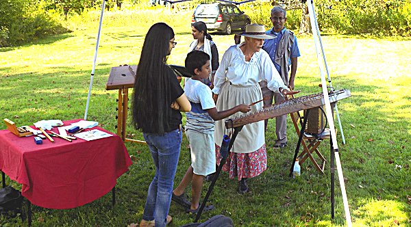 Gail Cashen (wearing a hat) demonstrates period instruments and allows visitors to try them out. Music at the Eight Square School House