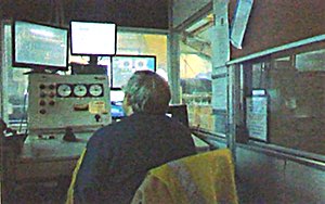 The shaft operator sits in front of computers that are hooked up to sensors and safety devices as well as operating the lift itself. While the operatior will be inside the shaft building at the new site several screens attached to security cameras around the site will allow the operator see whatever is going on on the property around him. (Photo by Cargill) Mine Shaft Operator