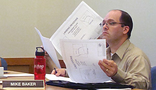 Planning Board member Mike Baker looks skeptically at plans for a 30 unit, three-story apartment complex Lansing Meadows