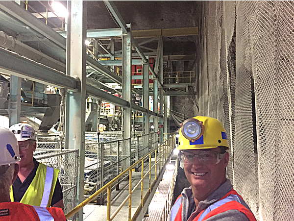 Lansing Councilman Robert Cree examines a crushing screen plant that is so tall it spans three veins of salt. Loaders convey the salt to crushers that break it down to chunks smaller than a football, then loads about 600 tons of salt per hour onto conveyor belts that carry the salt to the main tunnel. They deposit it on mainline conveyor belts that then take the salt through the crushing screen plant that reduces the rock salt to the size needed for the final product, and eventually to a shaft to be hoisted to the surface storage area north of Portland Point, and south of Myers Park. Robert Cree