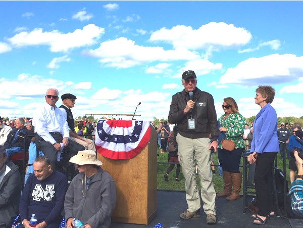 Ithaca-Tompkins Airport Manager Mike Hall (center, with microphone) gives a brief history of Ithaca aviation. Also shown (left to right) Borg Warner/Morse Systems Vice President of Global Manufacturing Steve Snyder, Announcer Stew Sommerville, Ithaca Acting Mayor Deborah Mohlenhoff, Tompkins County Legislature Chair Martha Robertson Tommy Come Home Historic Centennial Flight Ithaca-Tompkins Airport September 29, 2018