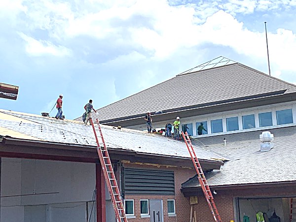 Roofers put shingles on the new concourse Wednesday Roofers