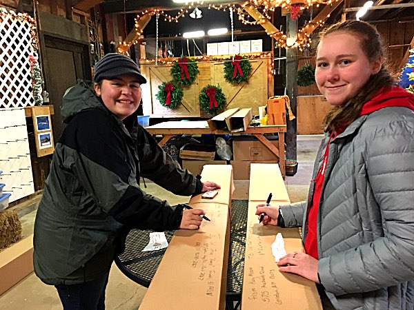 Aubryn Neubert and Morgan Wilcox address the 5 boxes after packing them with Christmas trees and stuffing them with letters and hand made decorations made by the LUMC junior and senior high youth mooretrees Aubryn Neubert Morgan Wilcox