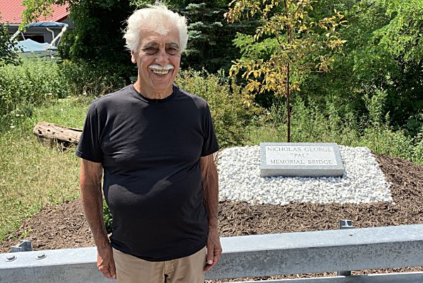 Marion George in front of a stone dedicating the bridge to his uncle Nicholas George Marion George