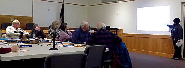 Patricia Van Every points to a plan of the Osmica project to illustrate the impact on her property of a proposed parking lot, and to advocate that the Planning Board require more plantings to buffer the lot from her property. Osmica Public Hearing